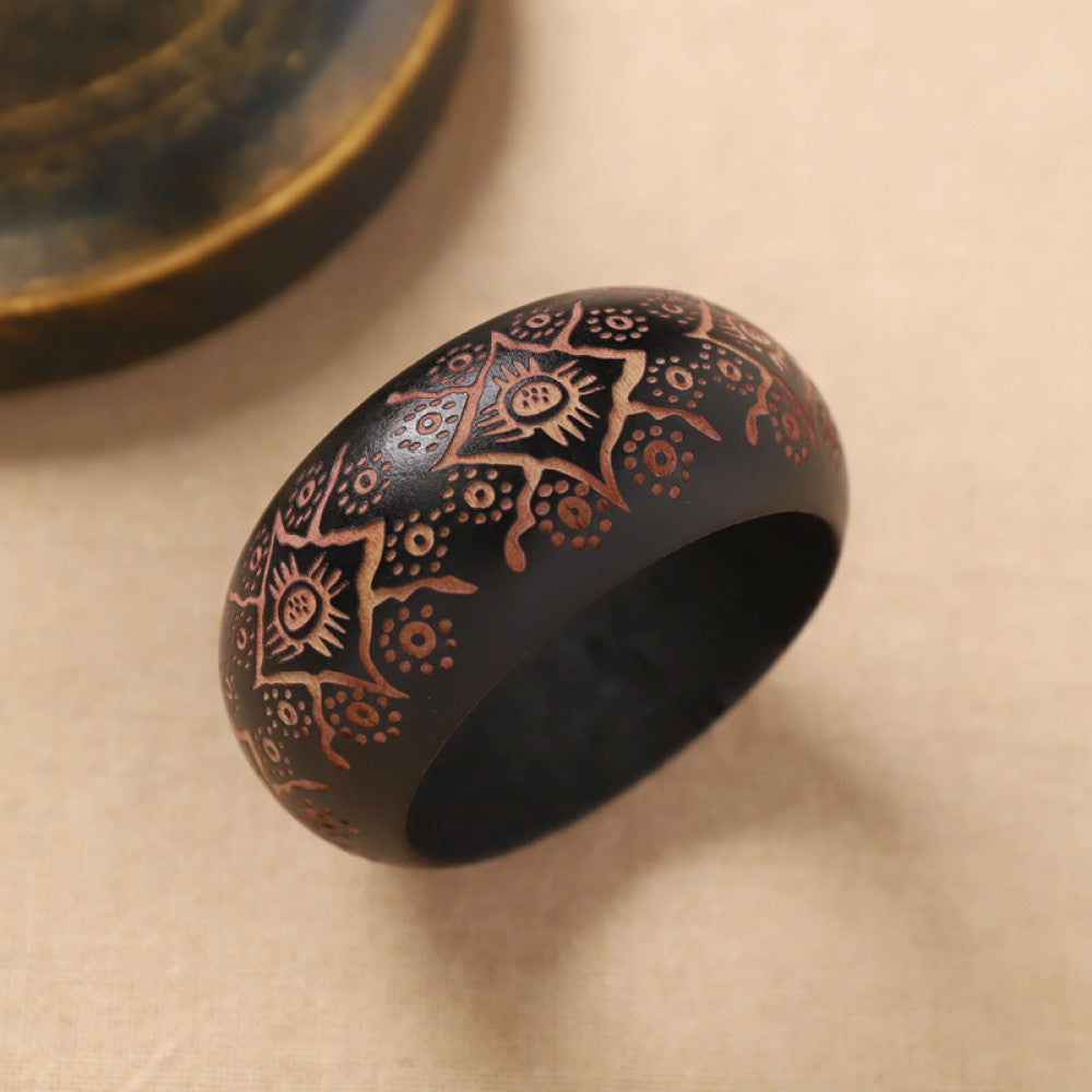 Boho vintage ethnic black bangle with sun motif filigree designs, styled on neutral surface, ideal for bohemian and tribal fashion enthusiasts in the US