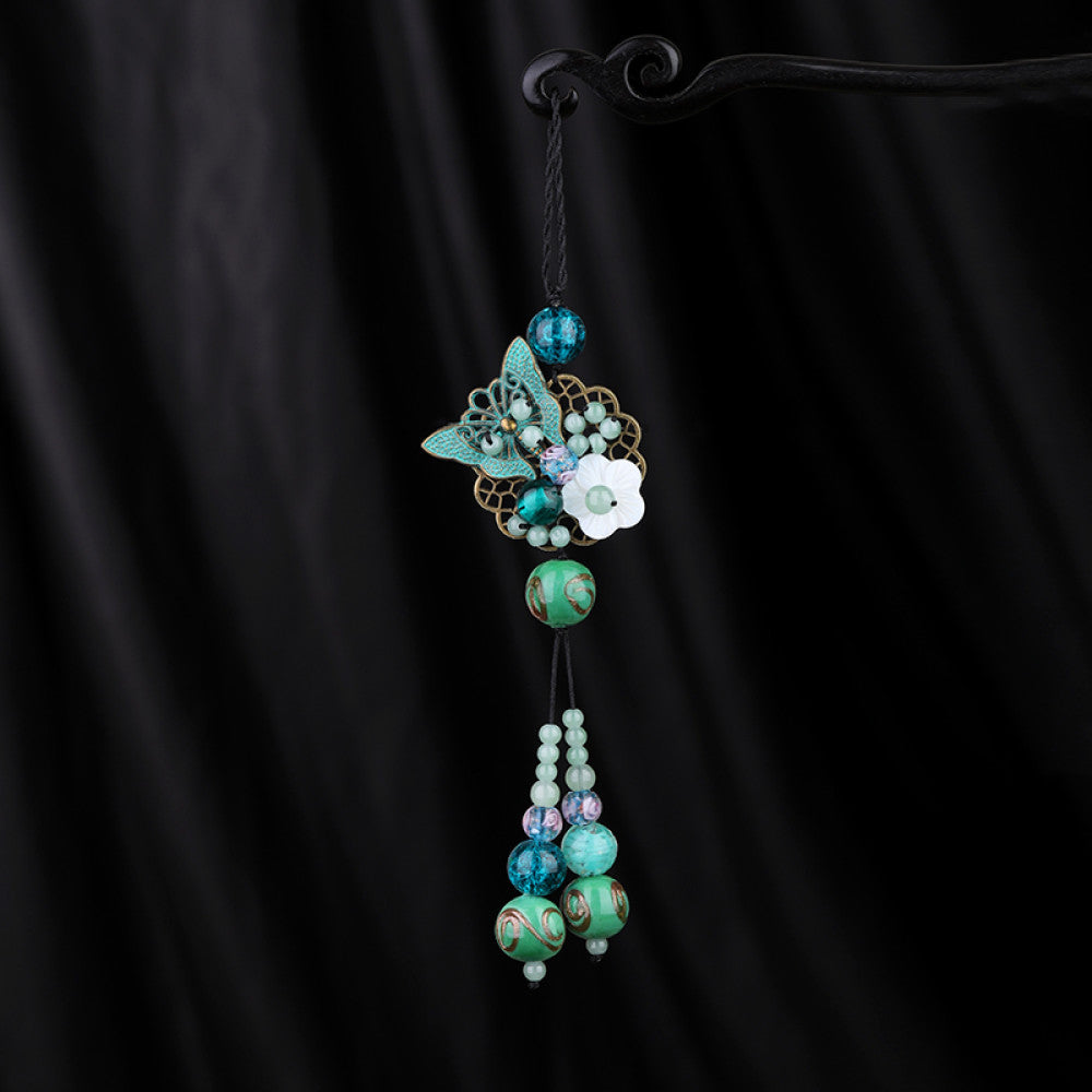 Boho vintage ethnic hair pendant with colorful turquoise/blue beaded tassels, butterfly accent and white flower charm, styled on a black fabric background, ideal for bohemian and traditional fashion enthusiasts in the US