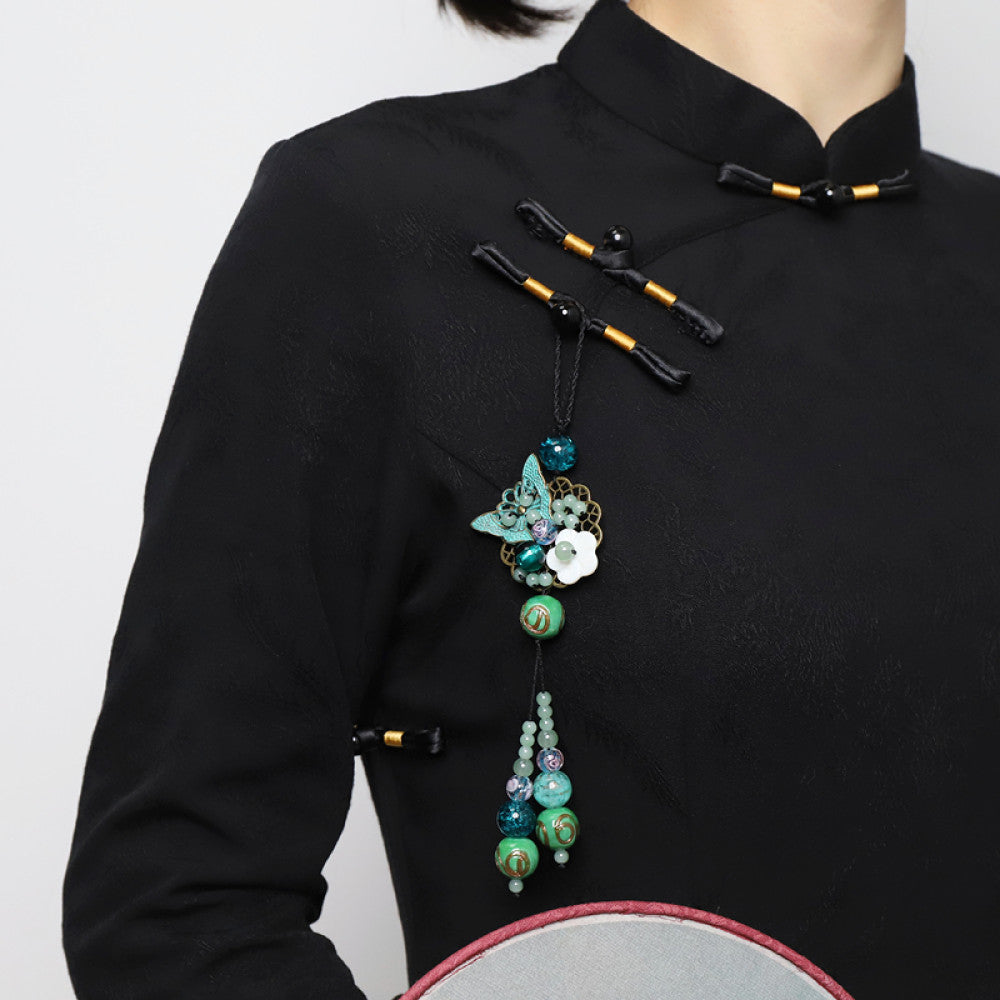Boho vintage ethnic hair pendant with colorful turquoise/blue beaded tassels, butterfly accent and white flower charm, styled on a black fabric background, ideal for bohemian and traditional fashion enthusiasts in the US 01