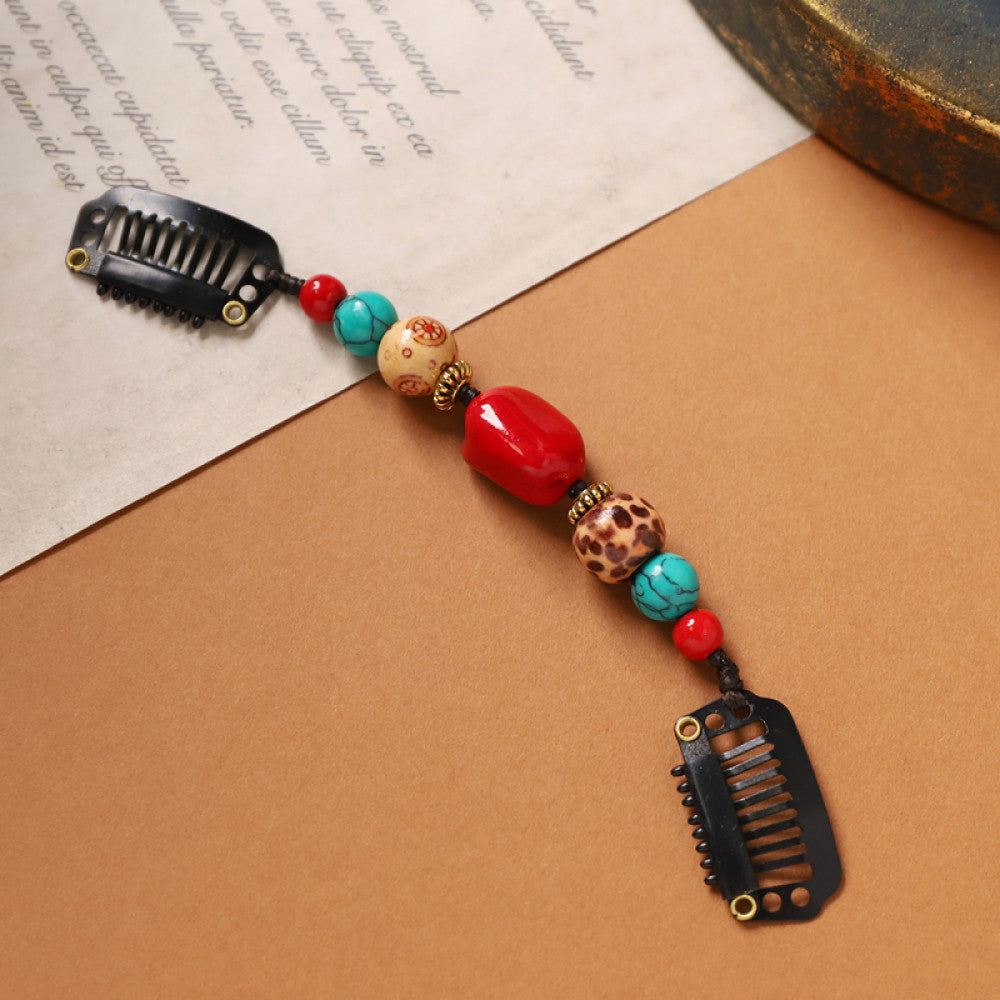 Boho vintage ethnic double hair comb ornament (displayed on a beige surface & text-printed paper background) featuring an evil eye decorative bead, red/yellow beads, and black hair combs