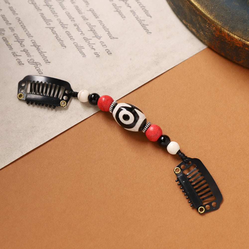 Boho vintage ethnic double hair comb ornament (displayed on a beige surface & text-printed paper background) featuring an evil eye decorative bead, red/yellow beads, and black hair combs 01