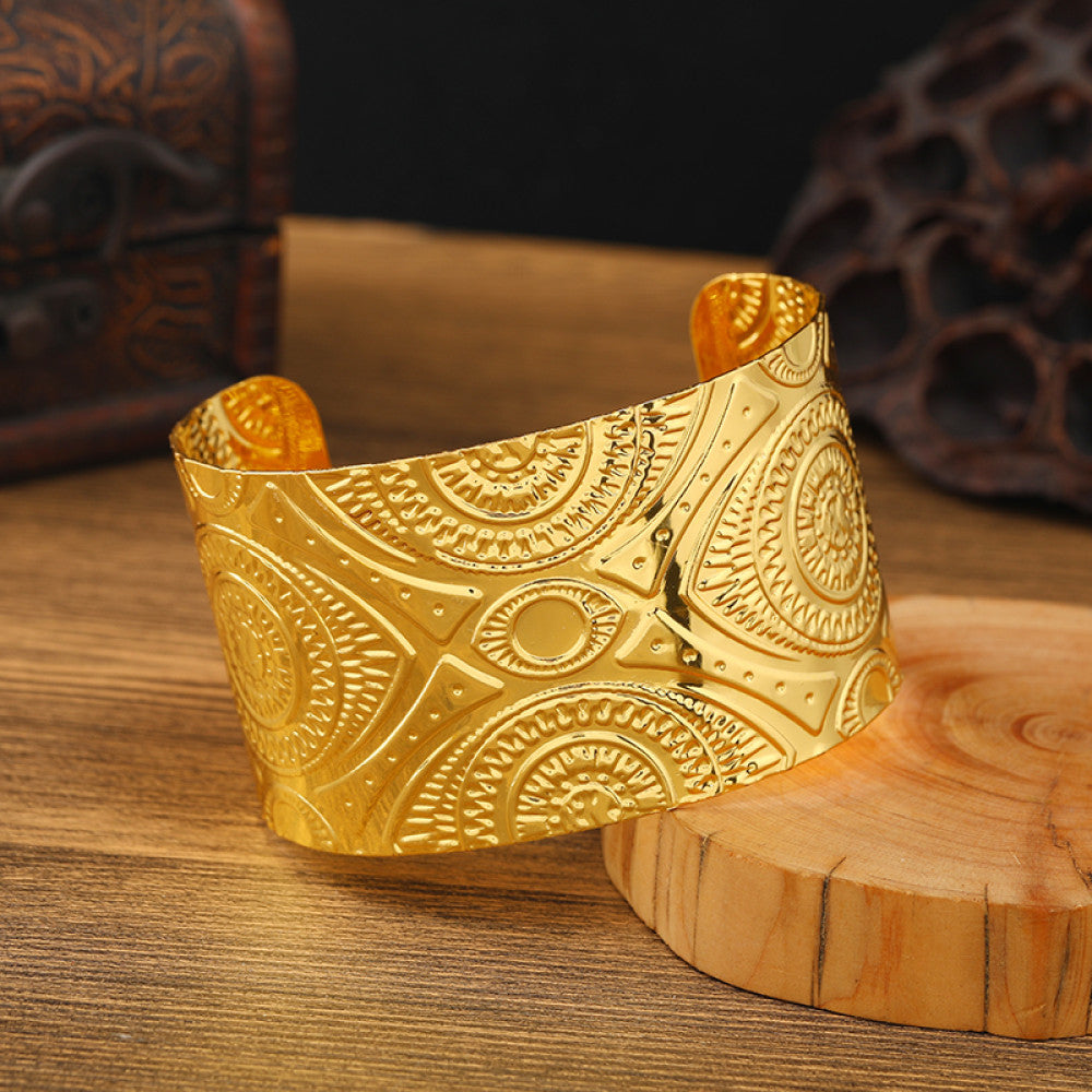 Boho vintage ethnic engraved gold cuff bangle with geometric designs, styled on wooden surface, ideal for bohemian and tribal fashion enthusiasts