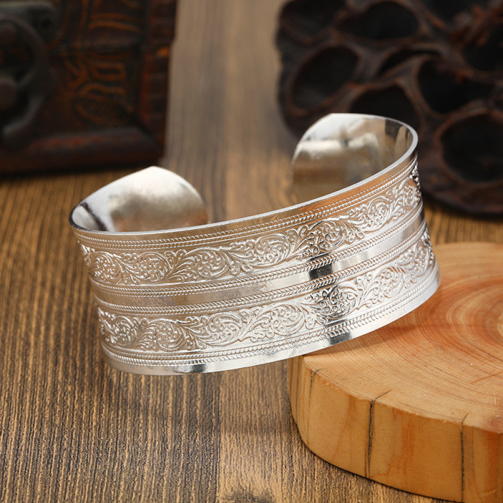 Boho vintage ethnic engraved silver cuff bangle with intricate floral designs, styled on wooden surface, ideal for bohemian and tribal fashion enthusiasts in the US