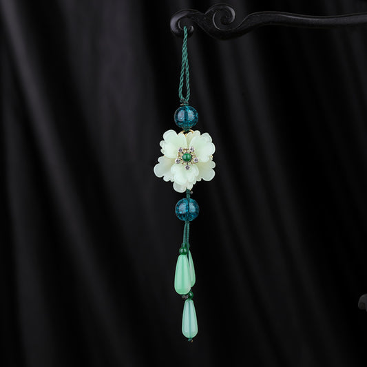 Boho vintage ethnic green-tone hair pendant featuring green cord, dark teal decorative beads, white flower charm (with gemstone center), and light green teardrop pendants, styled against a black fabric background, ideal for bohemian and traditional fashion enthusiasts in the US