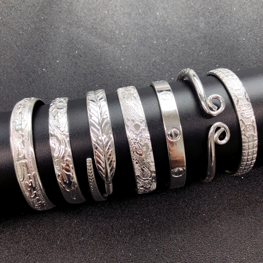 Assorted boho vintage ethnic silver bangle set with engraved and geometric designs, styled on a sleek surface, ideal for bohemian and tribal fashion enthusiasts