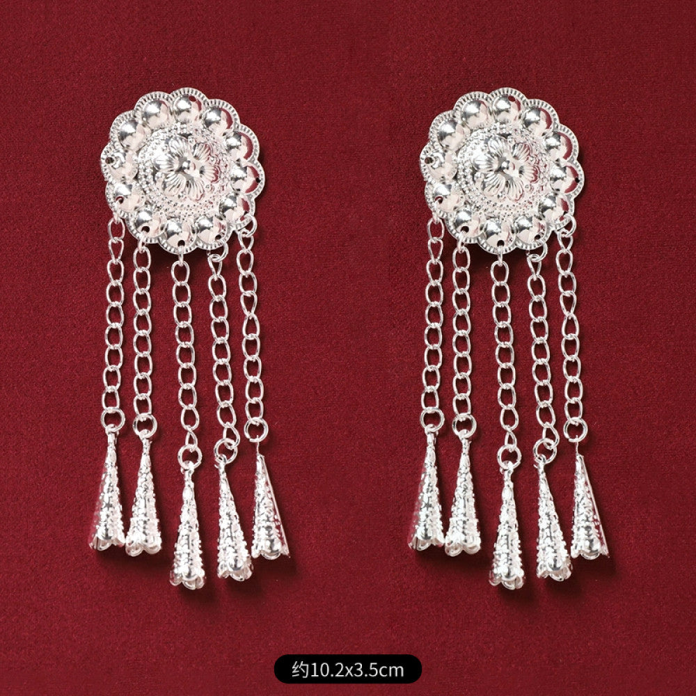 Pair of boho vintage ethnic silver-tone decorative ornaments, featuring intricate butterfly charms and layered bell tassel pendants, displayed on a rich red fabric background, ideal for bohemian and traditional fashion styling in the US