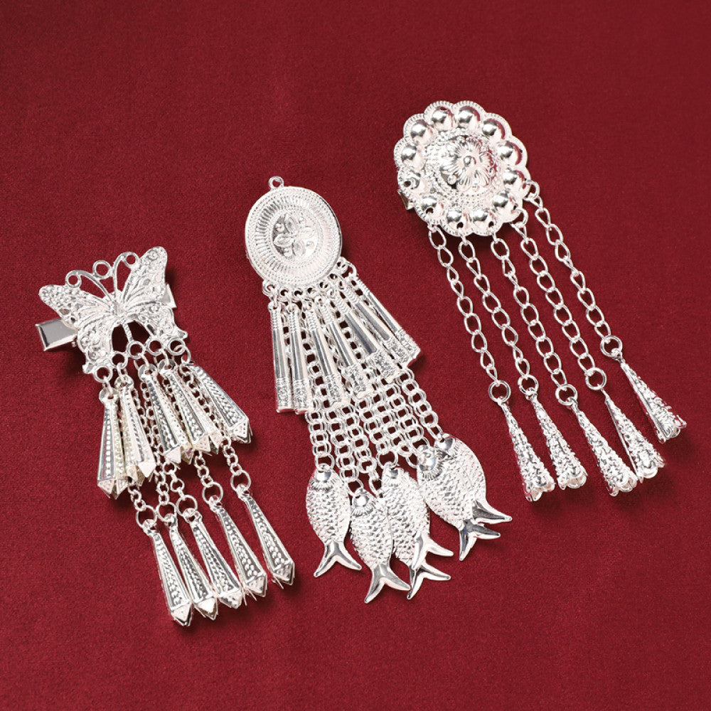 Pair of boho vintage ethnic silver-tone decorative ornaments, featuring intricate butterfly charms and layered bell tassel pendants, displayed on a rich red fabric background 03