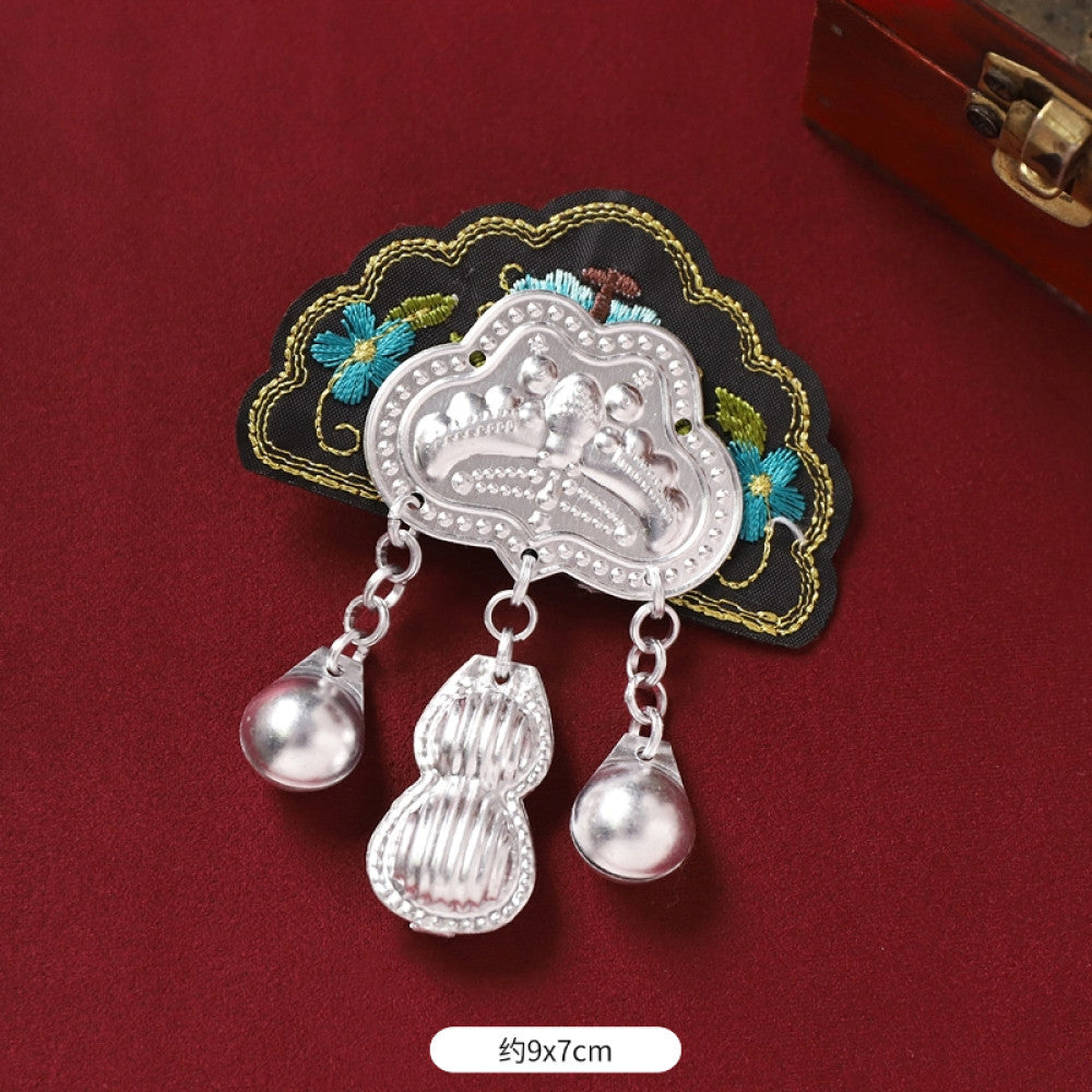 Boho vintage ethnic silver-tone decorative brooch featuring an intricate butterfly charm, pink floral embroidered accent (with blue details), and bell tassel pendants, displayed on a red fabric background  06