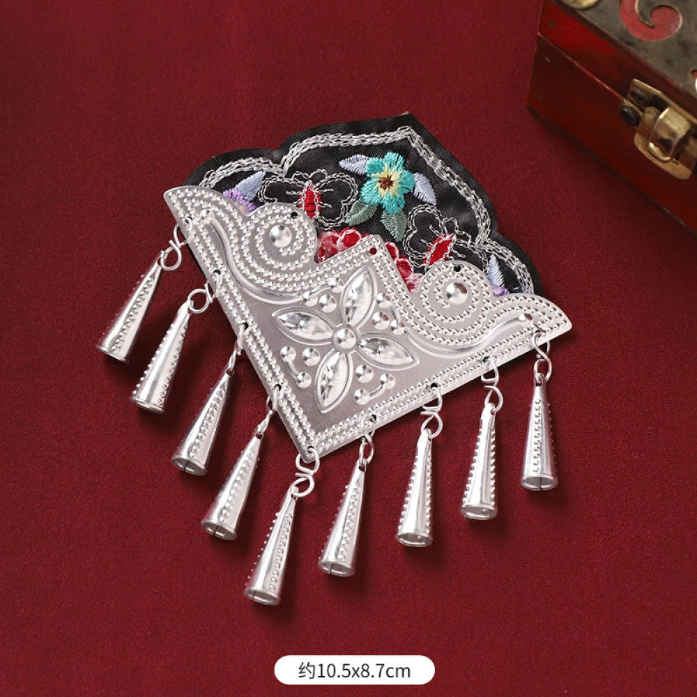 Boho vintage ethnic silver-tone decorative ornament featuring intricate silver-tone detailing, embroidered accent and multiple bell tassel pendants, displayed on a red fabric background 