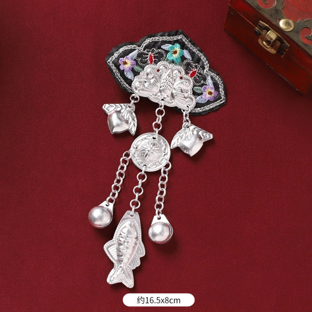 Boho vintage ethnic silver-tone decorative ornament featuring intricate silver-tone detailing, embroidered accent and multiple bell tassel pendants, displayed on a red fabric background  01