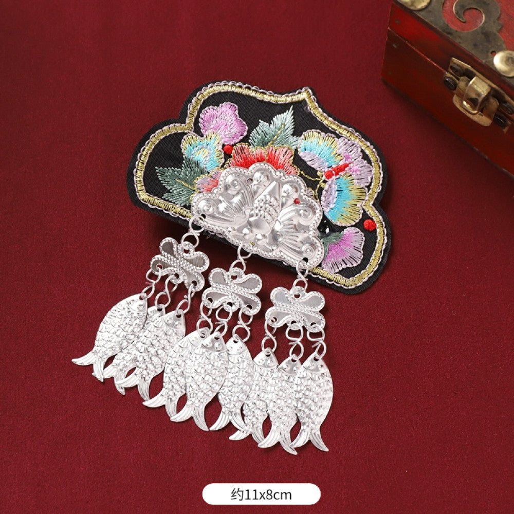 Boho vintage ethnic silver-tone decorative ornament featuring intricate silver-tone detailing, embroidered accent and multiple bell tassel pendants, displayed on a red fabric background  04