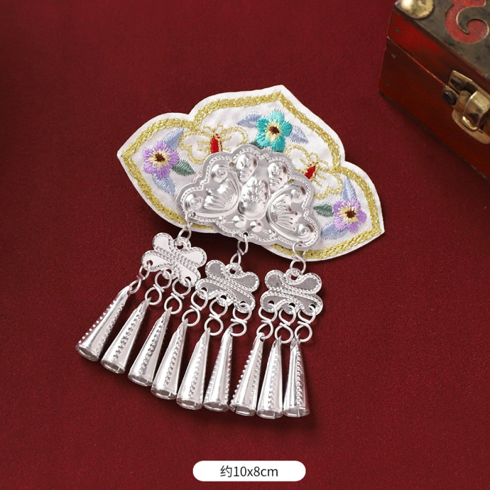 Boho vintage ethnic silver-tone decorative ornament featuring intricate silver-tone detailing, embroidered accent and multiple bell tassel pendants, displayed on a red fabric background  05
