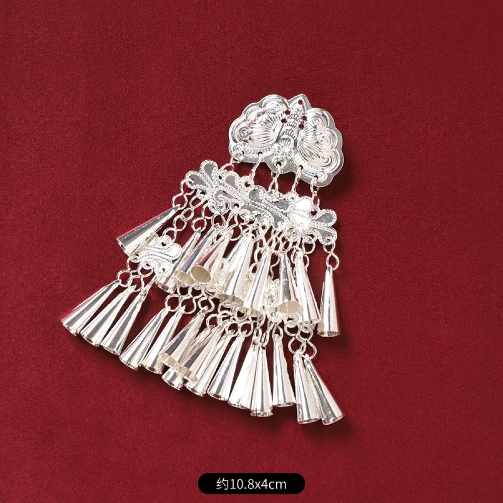 Boho vintage ethnic silver-tone decorative pendant featuring an intricate round patterned center, multiple silver-tone fish charms, and layered bell tassel fringe, displayed on a rich red fabric background 01