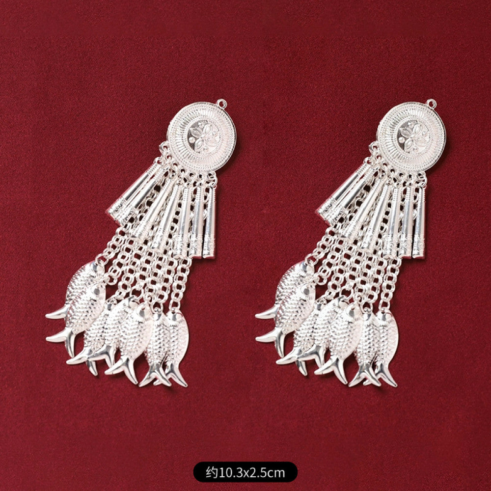 Boho vintage ethnic silver-tone decorative pendant featuring an intricate round patterned center, multiple silver-tone fish charms, and layered bell tassel fringe, displayed on a rich red fabric background 02