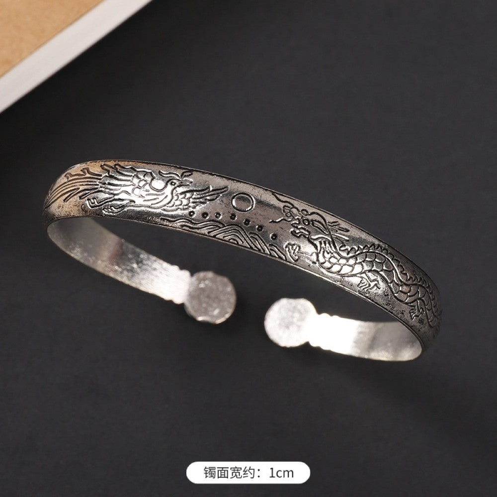 Vintage boho ethnic silver-tone cuff bracelet with dragon and phoenix engravings, styled on a black surface, ideal for bohemian and cultural fashion enthusiasts in the US