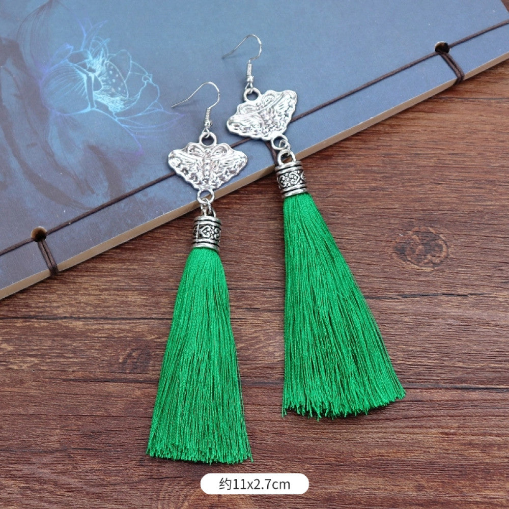 Boho vintage ethnic silver-tone earrings set (displayed on a wooden surface with a patterned notebook background) featuring embroidered lotus details and layered silver bell fringe pendants