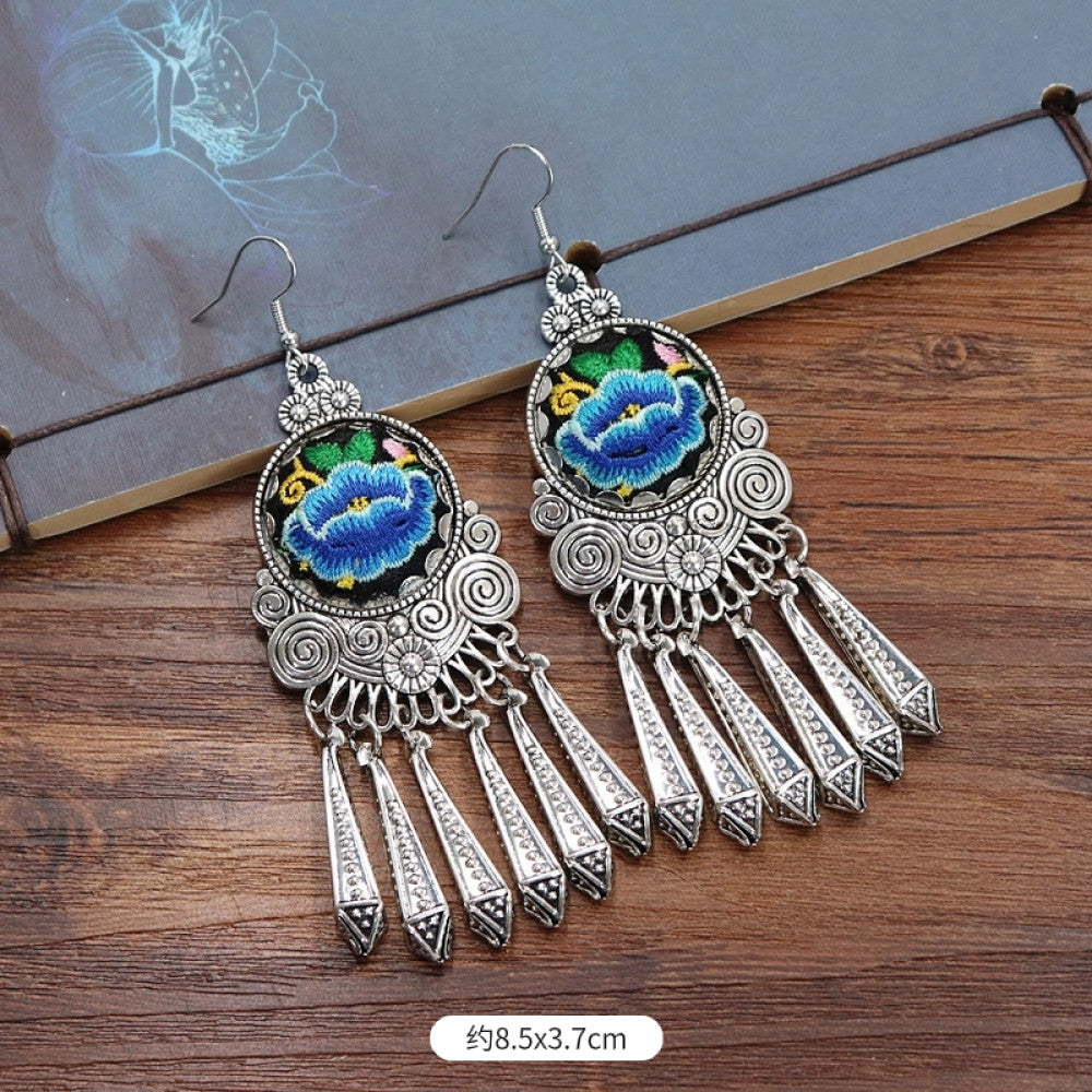 Boho vintage ethnic silver-tone earrings set (displayed on a wooden surface with a patterned notebook background) featuring embroidered lotus details and layered silver bell fringe pendants 01