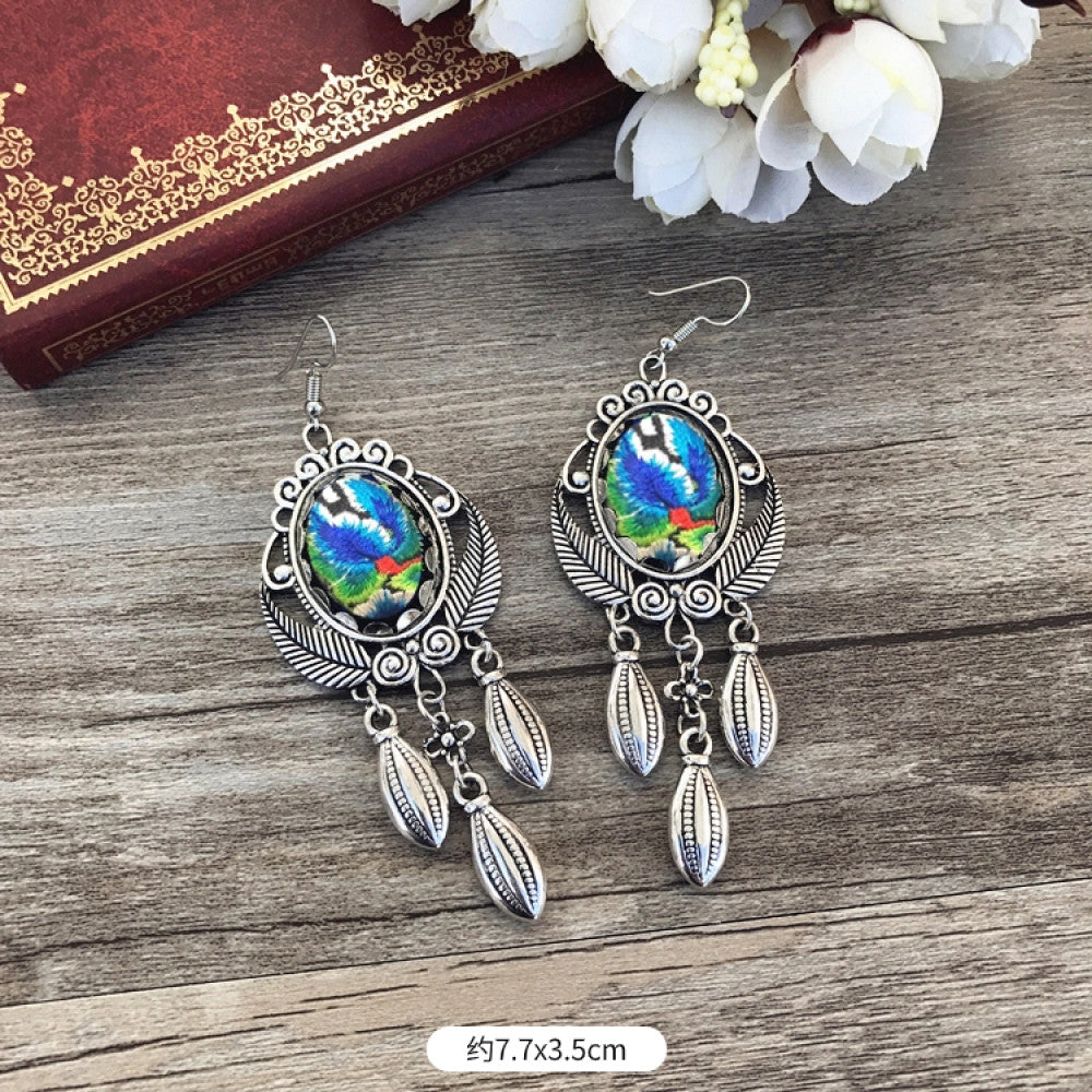 Boho vintage ethnic silver-tone earrings set (displayed on a wooden surface with a patterned notebook background) featuring embroidered lotus details and layered silver bell fringe pendants 02