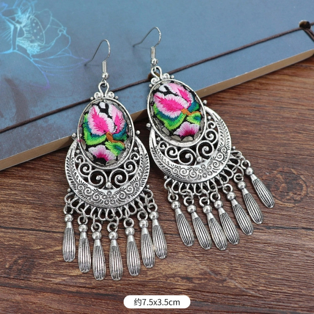 Boho vintage ethnic silver-tone earrings set (displayed on a wooden surface with a patterned notebook background) featuring embroidered lotus details and layered silver bell fringe pendants 03