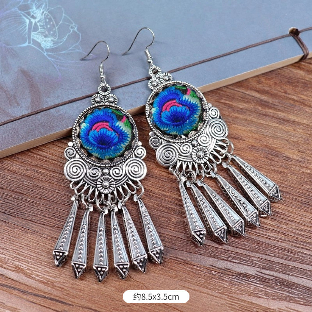 Boho vintage ethnic silver-tone earrings set (displayed on a wooden surface with a patterned notebook background) featuring embroidered lotus details and layered silver bell fringe pendants 05