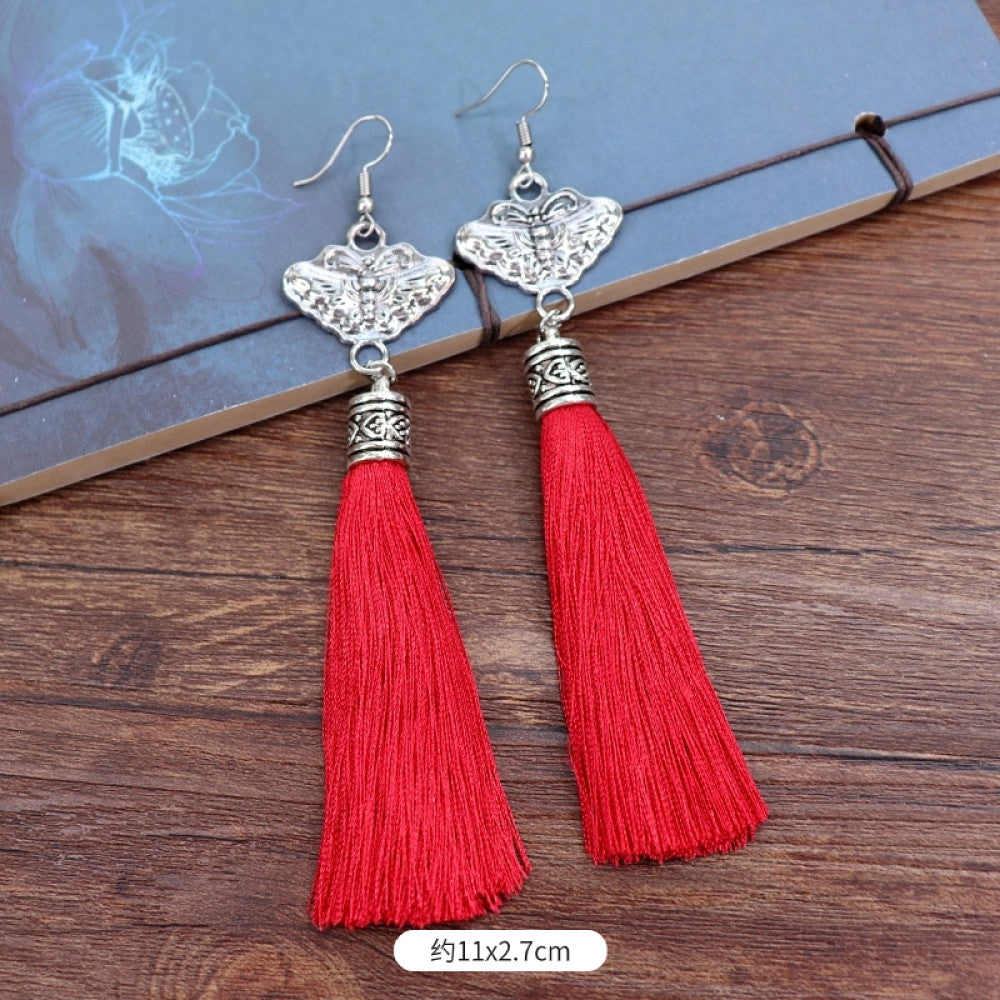 Boho vintage ethnic silver-tone earrings set (displayed on a wooden surface with a patterned notebook background) featuring embroidered lotus details and layered silver bell fringe pendants, ideal for bohemian retro or traditional fashion styling in the US 04