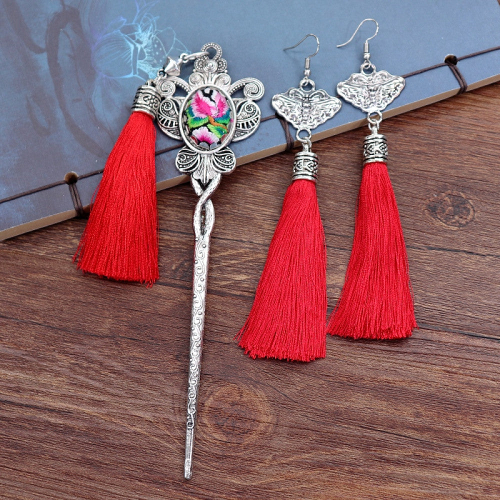 Boho vintage ethnic silver-tone hair stick & earring set (displayed on a blue background alongside white flowers) featuring ornate details, a colorful accent (on the hair stick), butterfly design (on earrings), and lush green tassels, ideal for bohemian retro or traditional fashion styling in the US 01