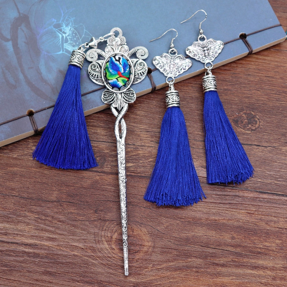 Boho vintage ethnic silver-tone hair stick & earring set (displayed on a blue background alongside white flowers) featuring ornate details, a colorful accent (on the hair stick), butterfly design (on earrings), and lush green tassels, ideal for bohemian retro or traditional fashion styling in the US 02
