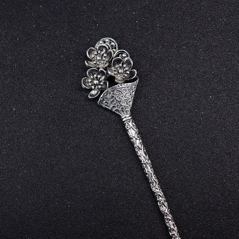 Boho vintage ethnic silver tone hair stick featuring a detailed flower cluster top and ornate carved pattern handle, displayed on a black glittery fabric background