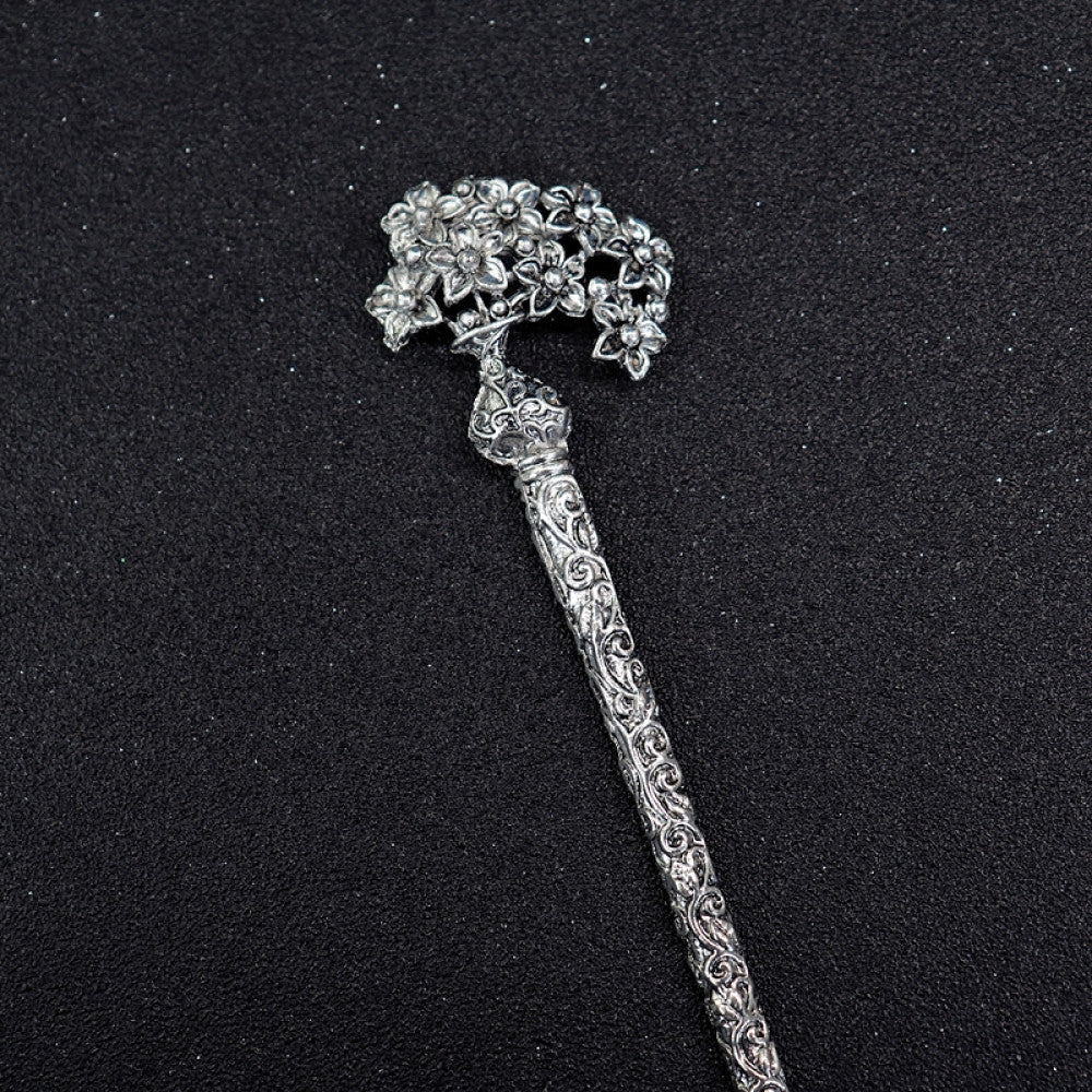Boho vintage ethnic silver tone hair stick featuring a detailed flower cluster top and ornate carved pattern handle, displayed on a black glittery fabric background, ideal for bohemian and traditional fashion enthusiasts in the US