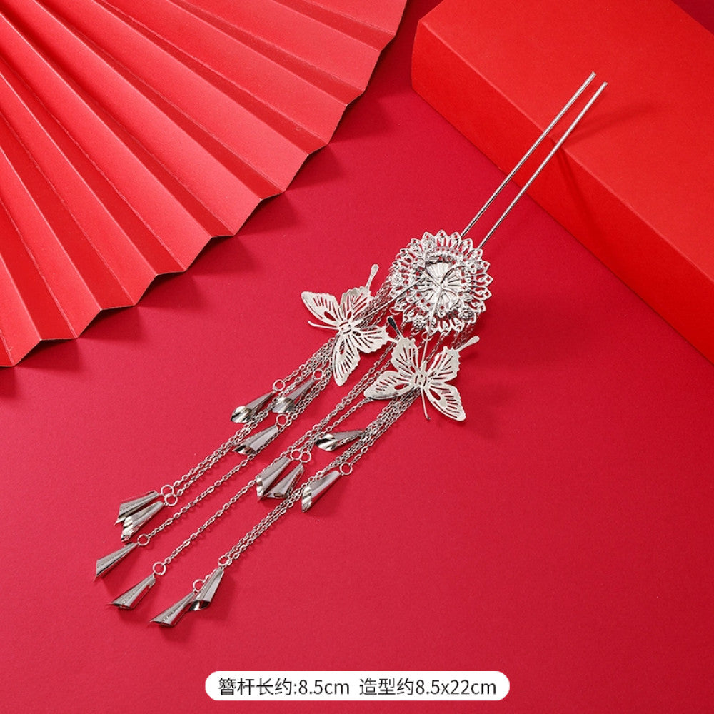 Boho vintage ethnic silver-tone hair stick (hand-held display against a rich red background alongside a red folding fan) featuring intricate openwork details and layered tassel fringe 04
