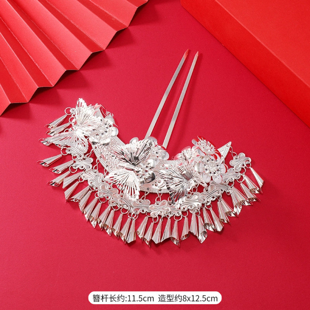 Boho vintage ethnic silver-tone hair stick (hand-held display against a rich red background alongside a red folding fan) featuring intricate openwork details and layered tassel fringe, ideal for bohemian retro or traditional Hanfu fashion styling in the US 02