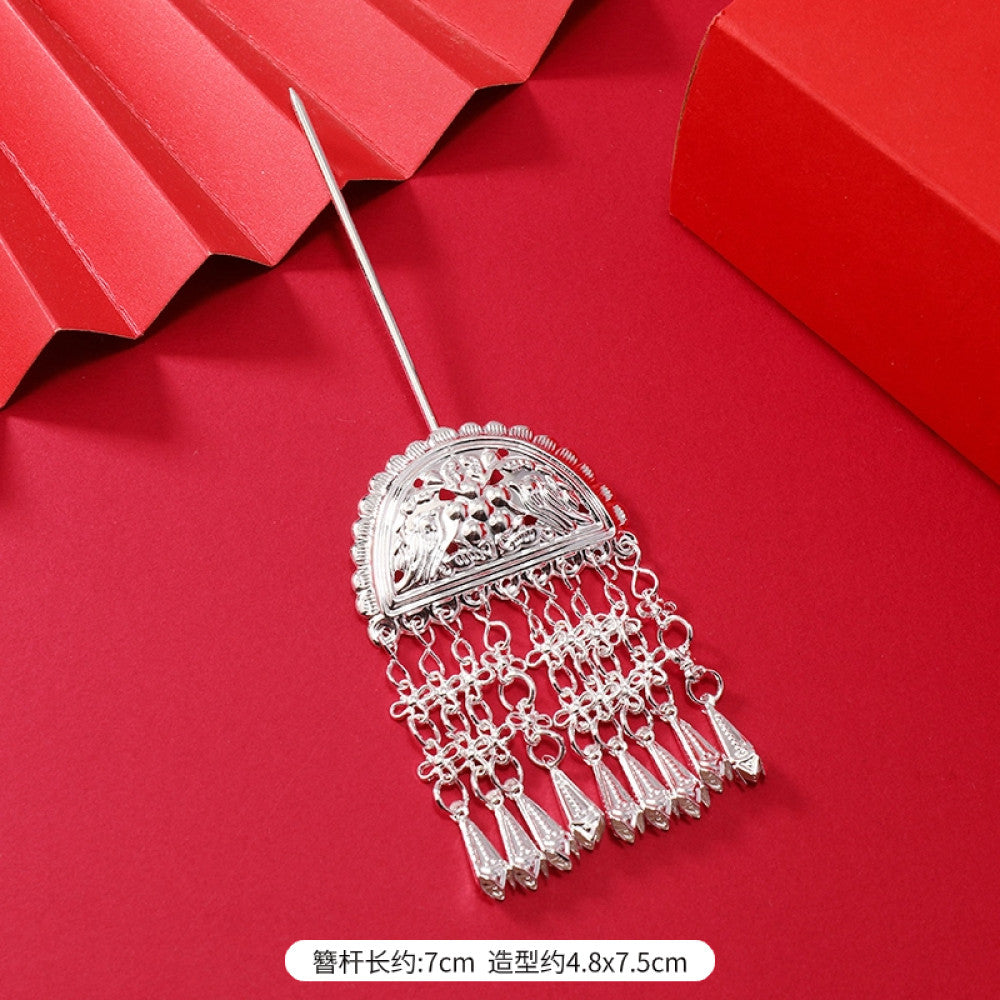 Boho vintage ethnic silver-tone hair stick (hand-held display against a rich red background alongside a red folding fan) featuring intricate openwork details and layered tassel fringe, ideal for bohemian retro or traditional Hanfu fashion styling in the US 03