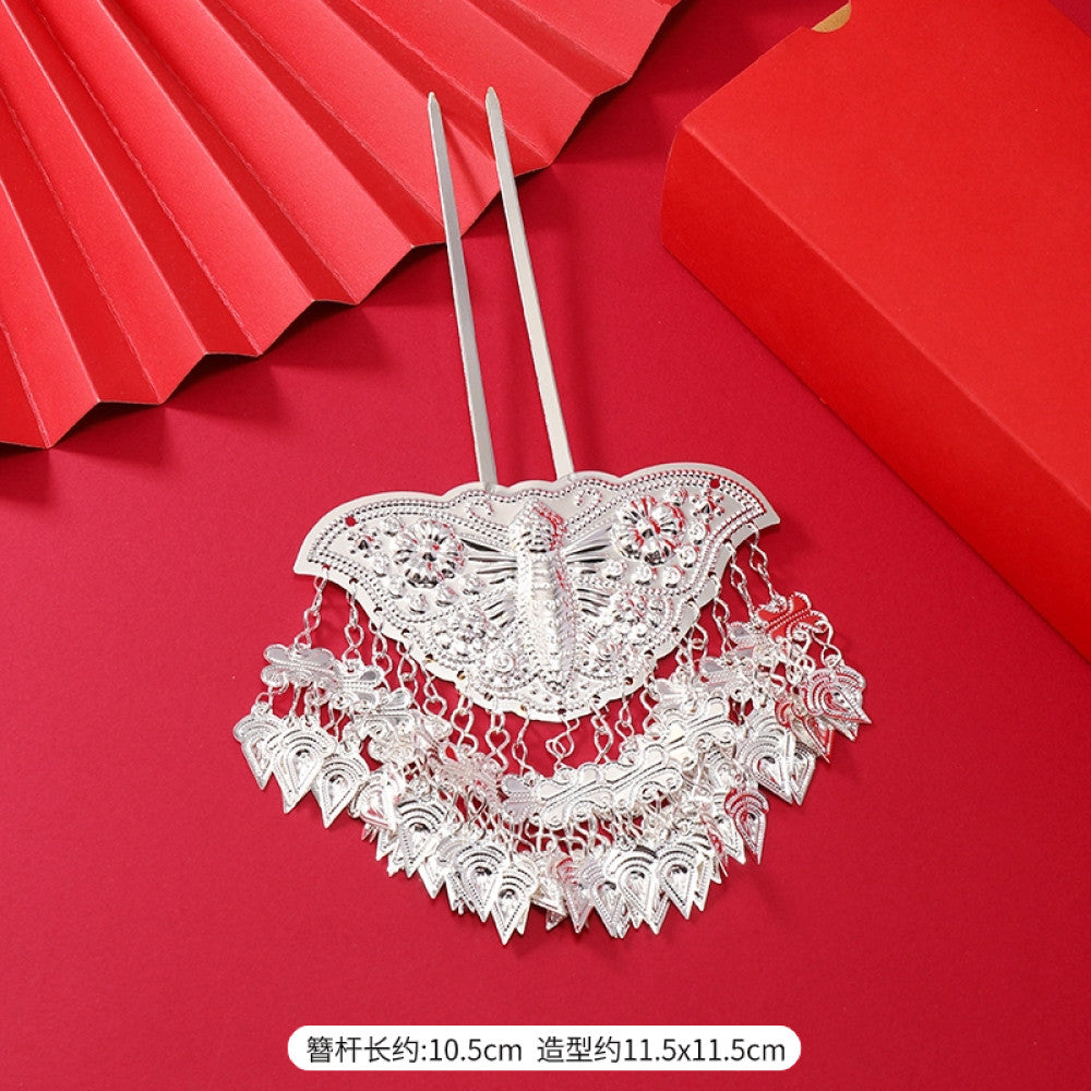 Boho vintage ethnic silver-tone hair stick (hand-held display against a rich red background alongside a red folding fan) featuring intricate openwork details and layered tassel fringe, ideal for bohemian retro or traditional Hanfu fashion styling in the US 04