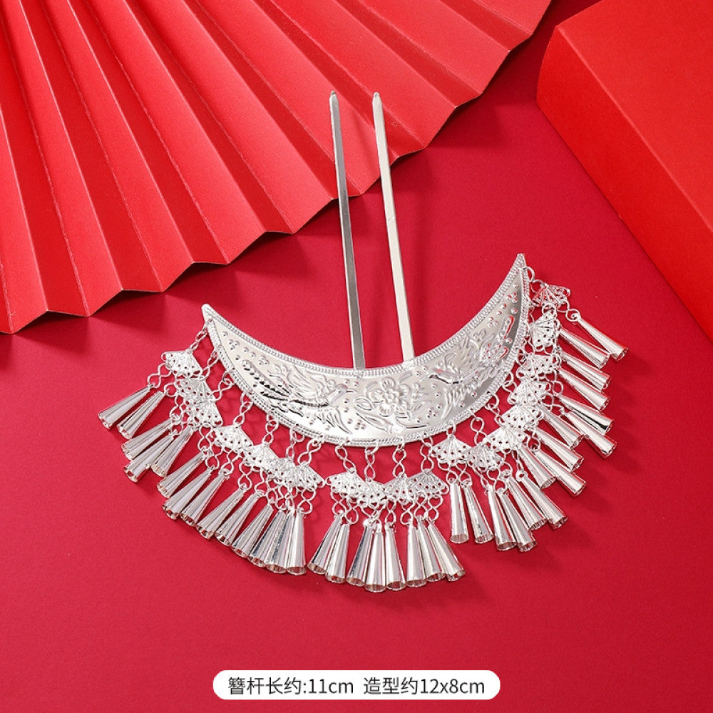 Boho vintage ethnic silver-tone hair stick (hand-held display against a rich red background alongside a red folding fan) featuring intricate openwork details and layered tassel fringe, ideal for bohemian retro or traditional Hanfu fashion styling in the US 06