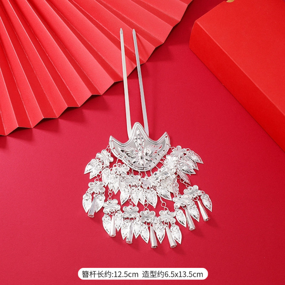 Boho vintage ethnic silver-tone hair stick (hand-held display against a rich red background alongside a red folding fan) featuring intricate openwork details and layered tassel fringe, ideal for bohemian retro or traditional Hanfu fashion styling in the US 07