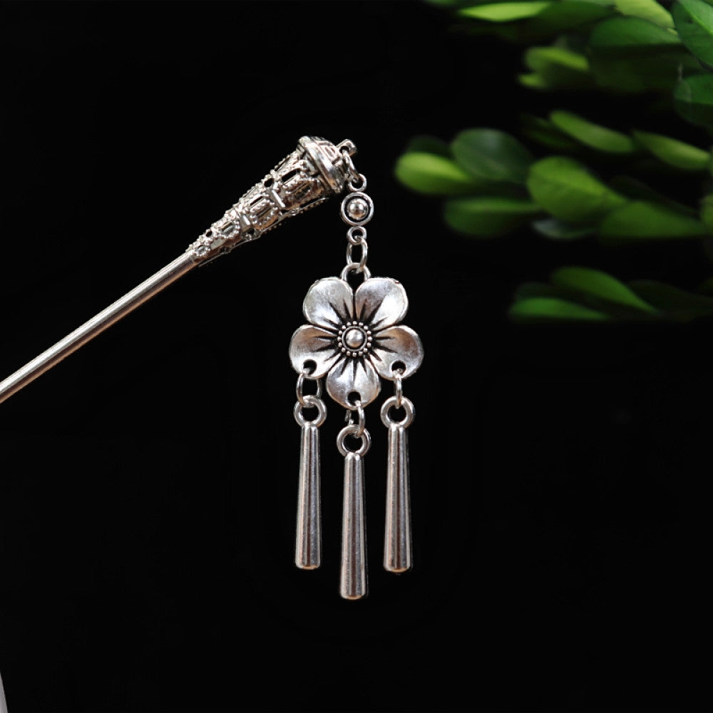 Boho vintage ethnic silver-tone hair stick featuring turquoise beads, an intricate round decorative element, and layered chain tassel fringe, displayed beside a white vessel green foliage 05