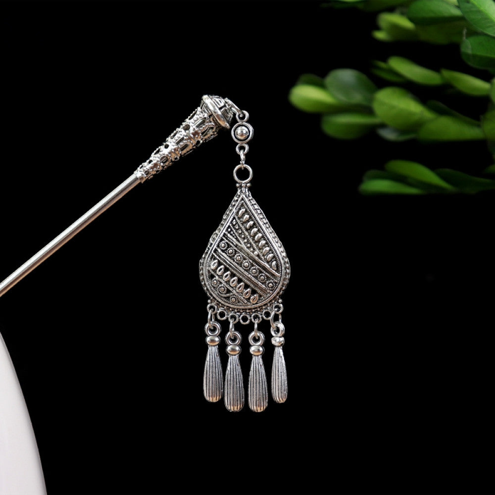 Boho vintage ethnic silver-tone hair stick featuring turquoise beads, an intricate round decorative element, and layered chain tassel fringe, displayed beside a white vessel green foliage , ideal for bohemian and traditional fashion enthusiasts in the US 01