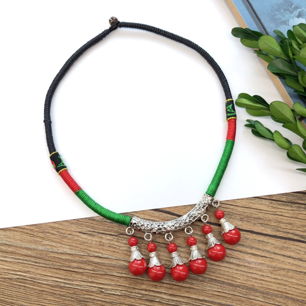 Boho vintage ethnic tri-color rope choker necklace, featuring a silver-tone ornate fringe pendant with colorful bead details, displayed on a wooden surface