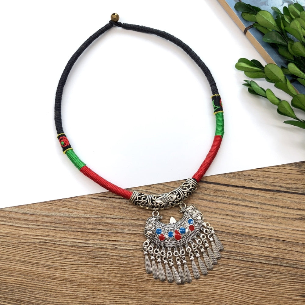 Boho vintage ethnic tri-color (black/red/green) rope choker necklace, featuring a silver-tone ornate fringe pendant with colorful bead details, displayed on a wooden surface (paired with white background, green foliage & a notebook), ideal for bohemian casual fashion styling in the US