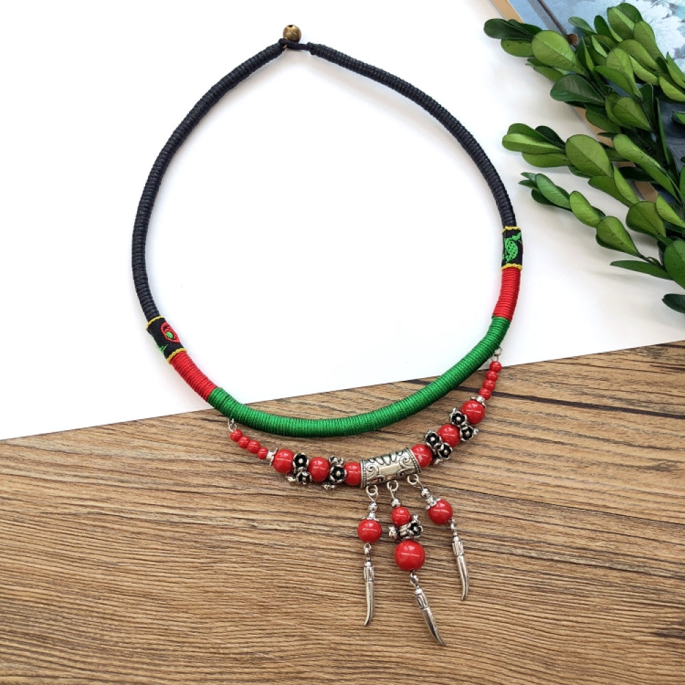 Boho vintage ethnic tri-color (black/red/green) rope choker necklace, featuring a silver-tone ornate fringe pendant with colorful bead details, displayed on a wooden surface (paired with white background, green foliage & a notebook), ideal for bohemian casual fashion styling in the US 02