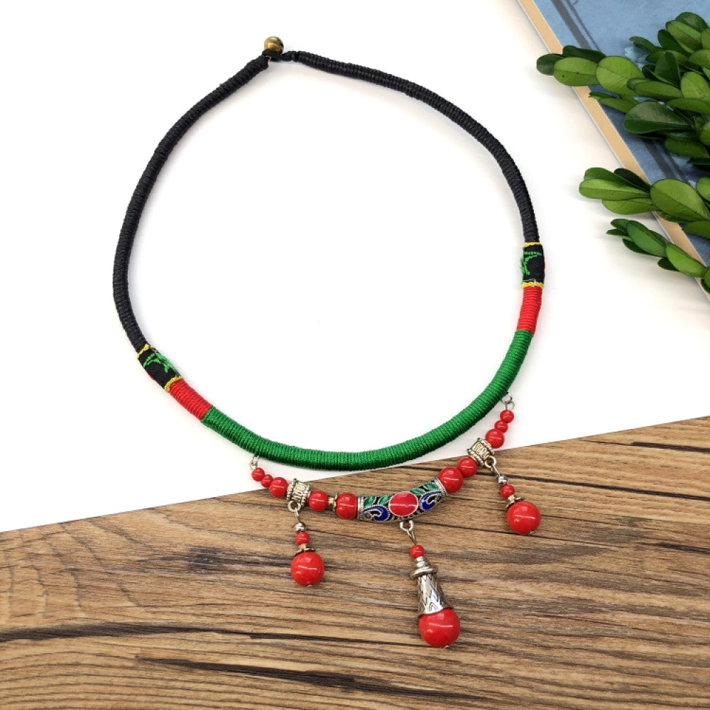 Boho vintage ethnic tri-color (black/red/green) rope choker necklace, featuring a silver-tone ornate fringe pendant with colorful bead details, displayed on a wooden surface (paired with white background, green foliage & a notebook), ideal for bohemian casual fashion styling in the US 04