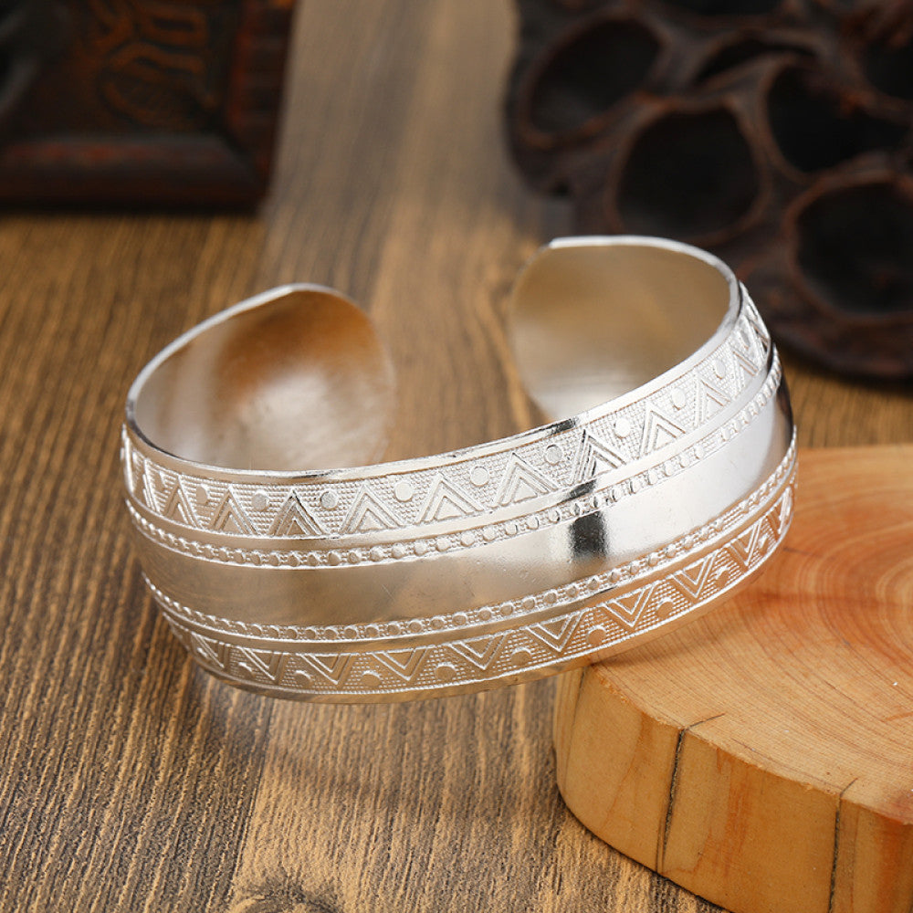 Boho vintage ethnic silver cuff bangle with tribal geometric engravings, styled on wooden surface, perfect for bohemian and tribal fashion lovers in the US