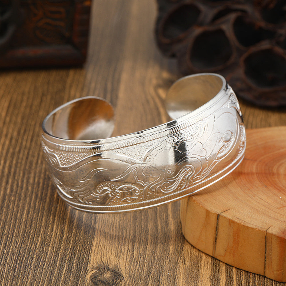 Boho vintage ethnic silver cuff bangle with tribal geometric engravings, styled on wooden surface, perfect for bohemian and tribal fashion lovers in the US 09