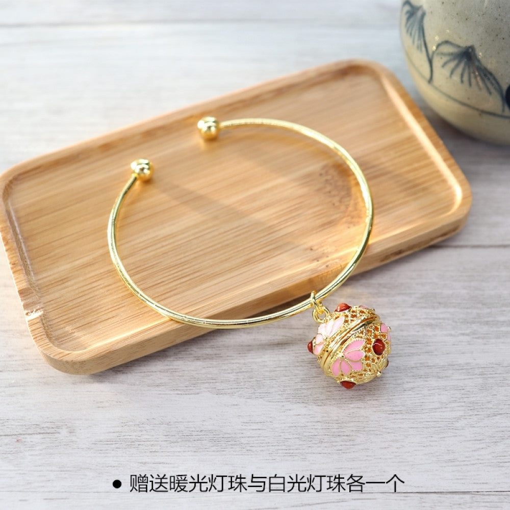 Boho vintage gold bangle with sakura locket charm, styled on wooden tray, ideal for bohemian and floral fashion enthusiasts