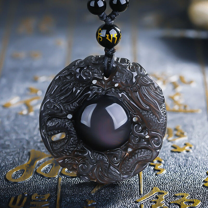 A necklace featuring a carved ice - type obsidian pendant with a dragon pattern, a central obsidian bead, and black obsidian beads, including a bead with yellow inscriptions.