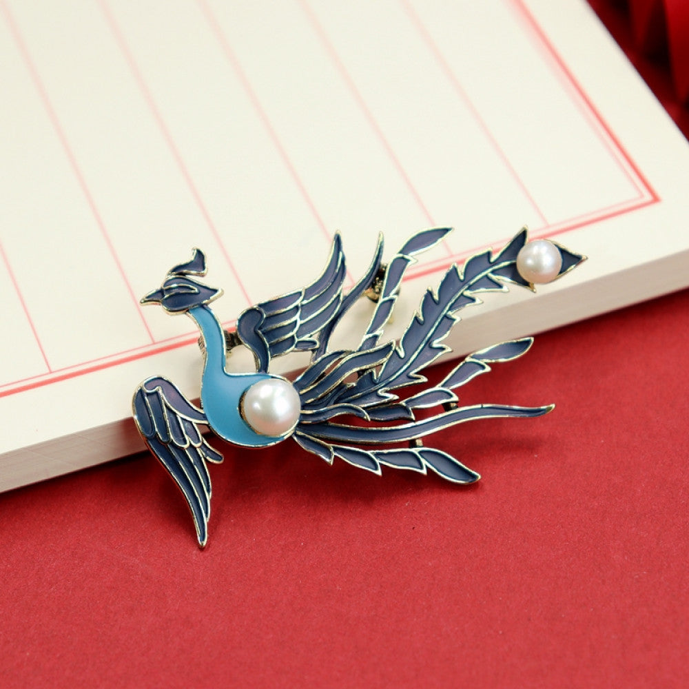 Inspired by the traditional Chinese phoenix, this brooch uses enamel craftsmanship to outline a vivid phoenix. Its blue-purple wings are layered, and two lustrous pearls add a touch of elegance.