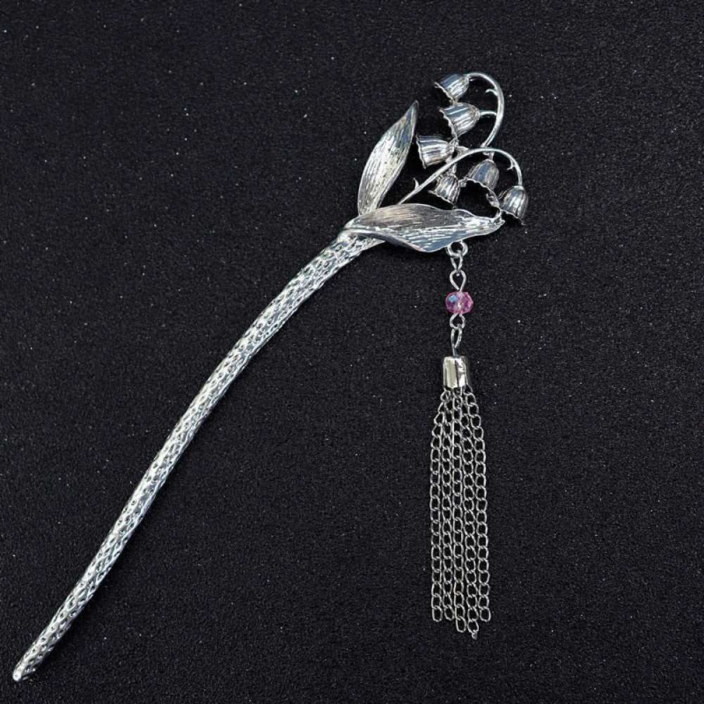 ethnic silver tone hair stick featuring a detailed flower cluster top and ornate carved pattern handle, displayed on a black glittery fabric background