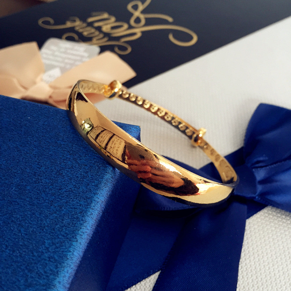 Fashion gold-tone adjustable bangle with sleek design, displayed on blue gift box with ribbon, ideal for luxury and contemporary fashion enthusiasts