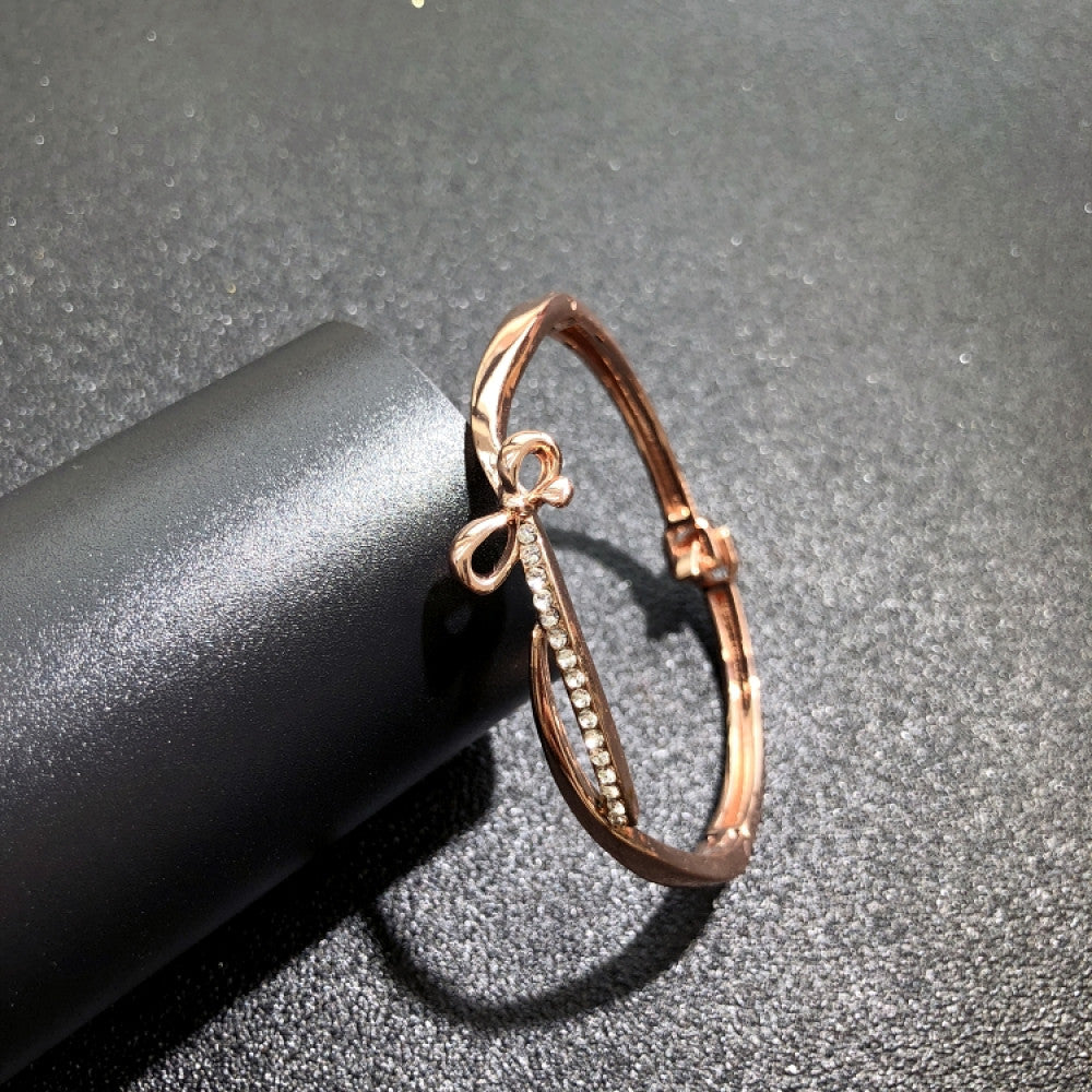 Fashion luxury rose gold bangle with diamond-encrusted signature logo, displayed on black surface, ideal for luxury fashion and statement jewelry enthusiasts 05