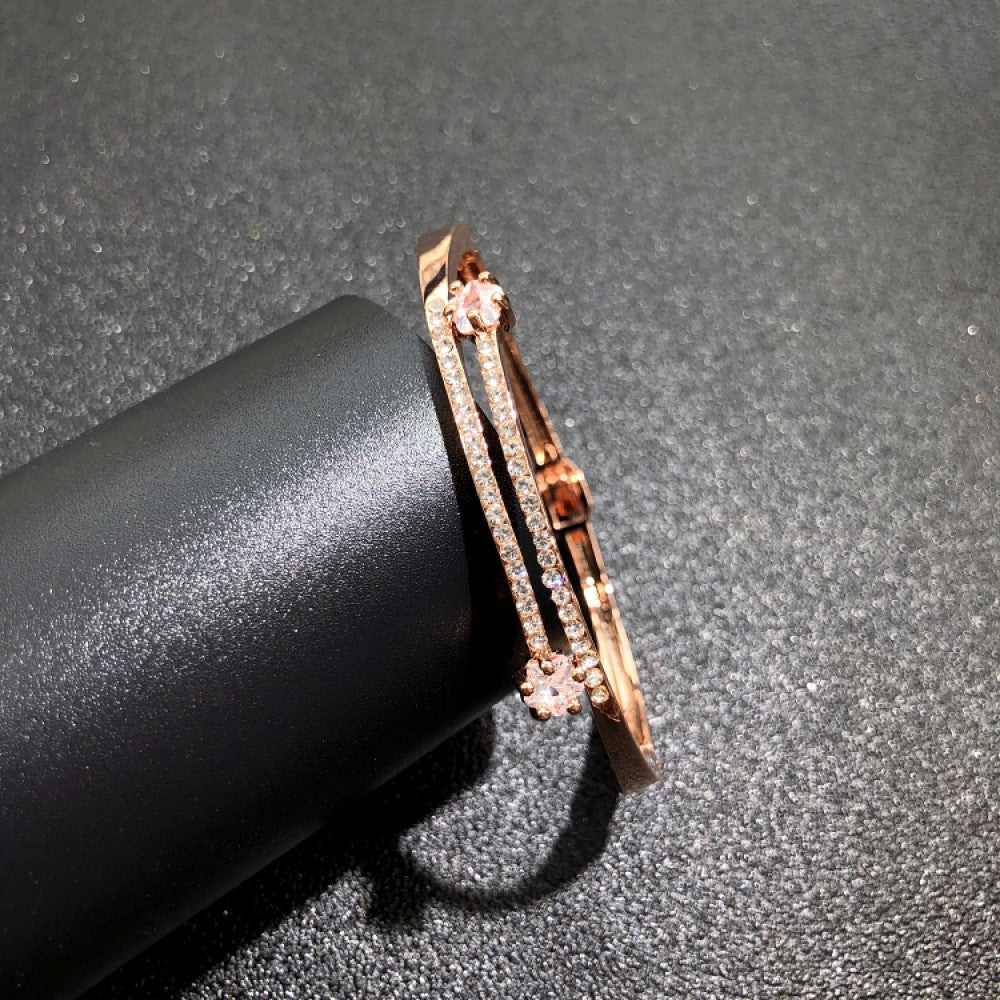 Fashion luxury rose gold bangle with diamond-encrusted signature logo, displayed on black surface, ideal for luxury fashion and statement jewelry enthusiasts 06